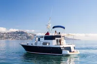 Nimbus 380 Commander 2005 yacht cruising on calm sea with scenic coastal backdrop.