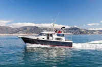 Nimbus 380 Commander 2005 cruising on clear blue waters with scenic mountain backdrop.