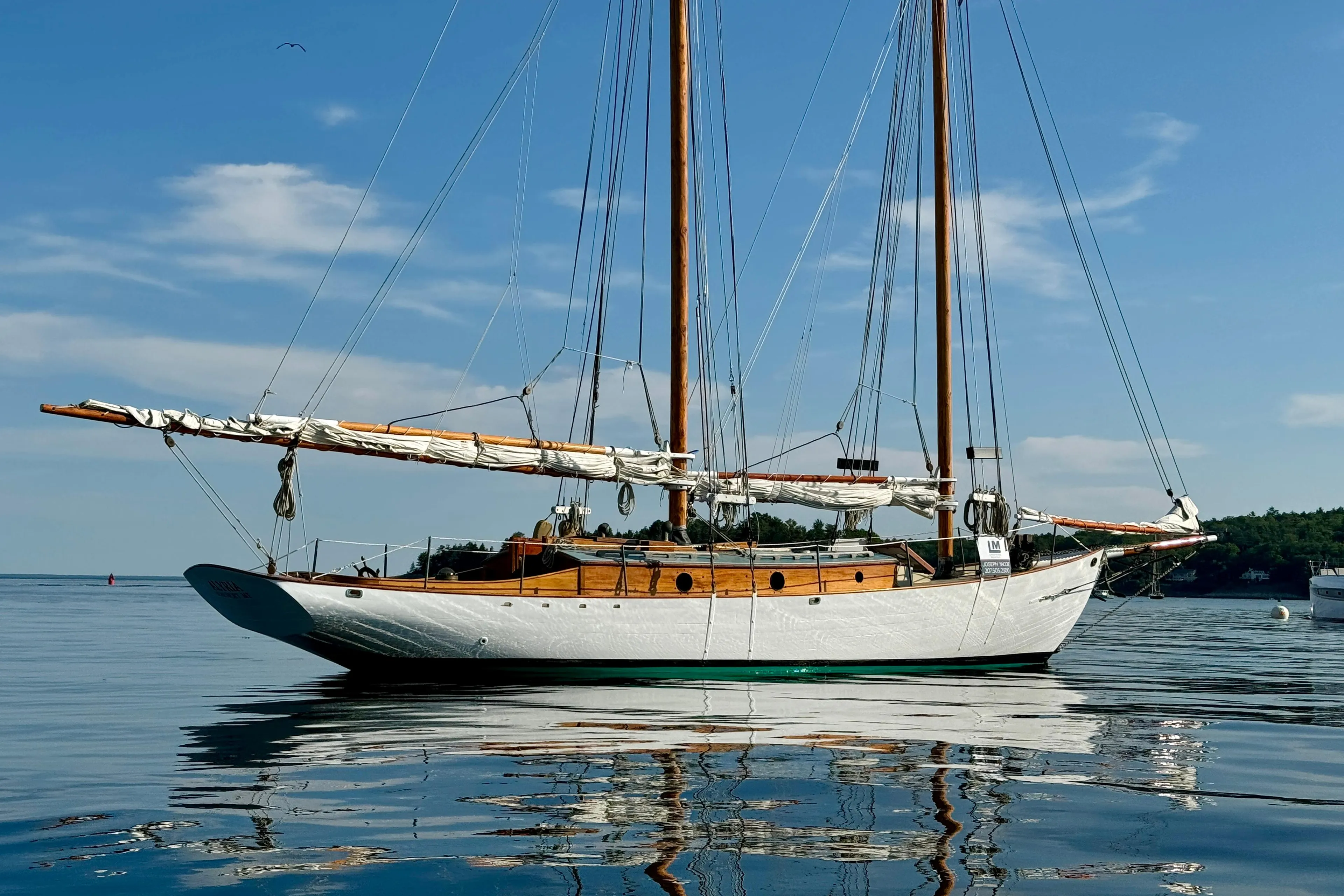 Sailing yacht "John Alden Malabar II" on calm waters, 1996 model, under clear blue sky.