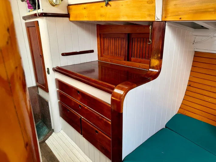Alyria Yacht Photos Pics Interior of 1996 Custom John Alden Malabar II with wooden cabinetry and teal seating.