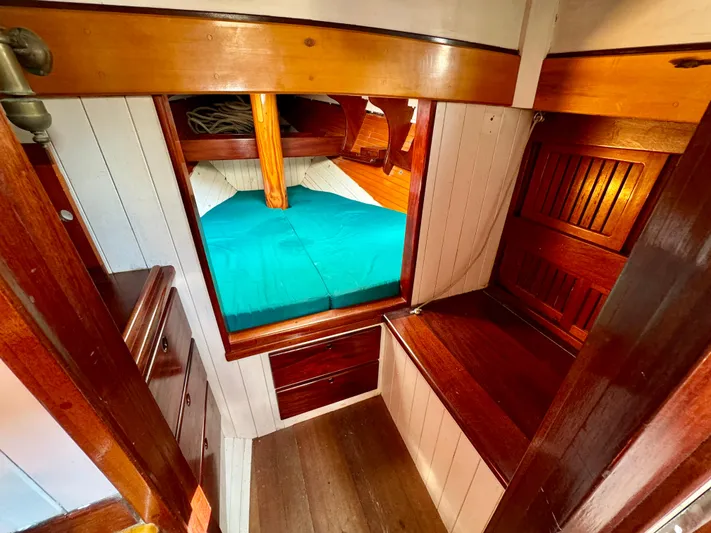 Alyria Yacht Photos Pics Cozy cabin interior of 1996 Custom John Alden Malabar II with wooden furnishings and teal bedding.