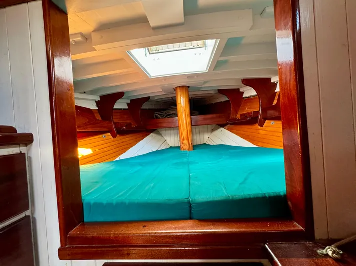 Alyria Yacht Photos Pics Interior of 1996 Custom John Alden Malabar II sailboat with wooden finish and teal bedding.