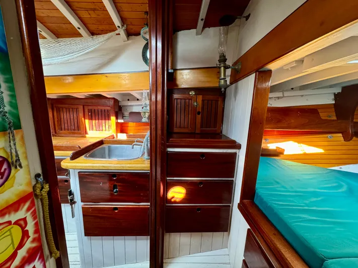 Alyria Yacht Photos Pics Interior of 1996 Custom John Alden Malabar II sailboat with wooden cabinetry and cozy sleeping area.