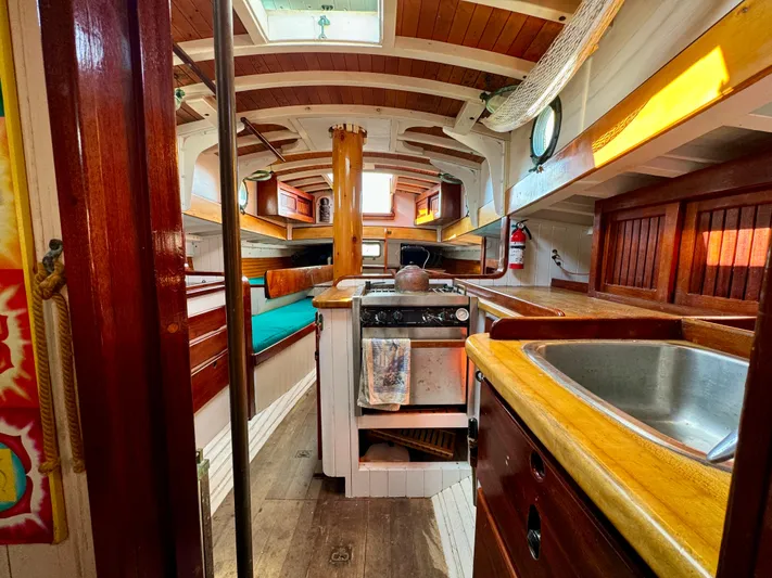 Alyria Yacht Photos Pics Interior of 1996 Custom John Alden Malabar II sailboat with wooden finishes and compact kitchen.
