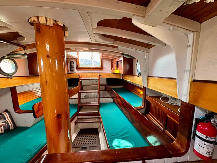 Alyria Yacht Photos Pics Interior of 1996 Custom John Alden Malabar II sailboat with wooden finishes and green cushions.