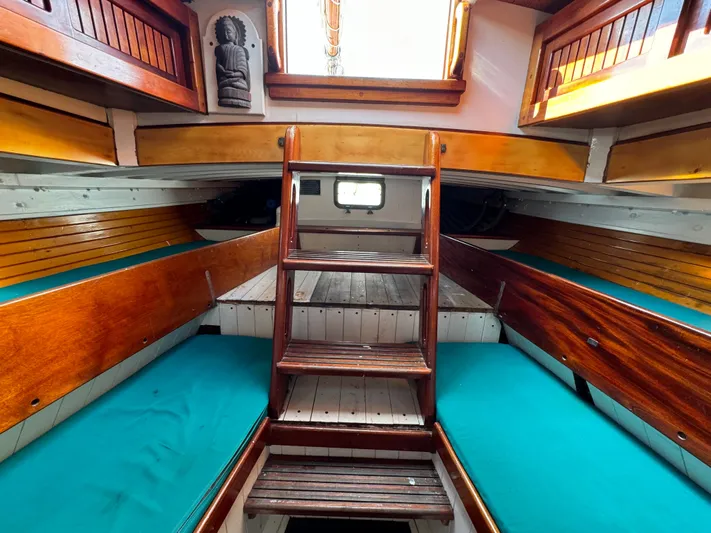 Alyria Yacht Photos Pics Interior of 1996 Custom John Alden Malabar II sailboat with wooden finishes and teal cushions.