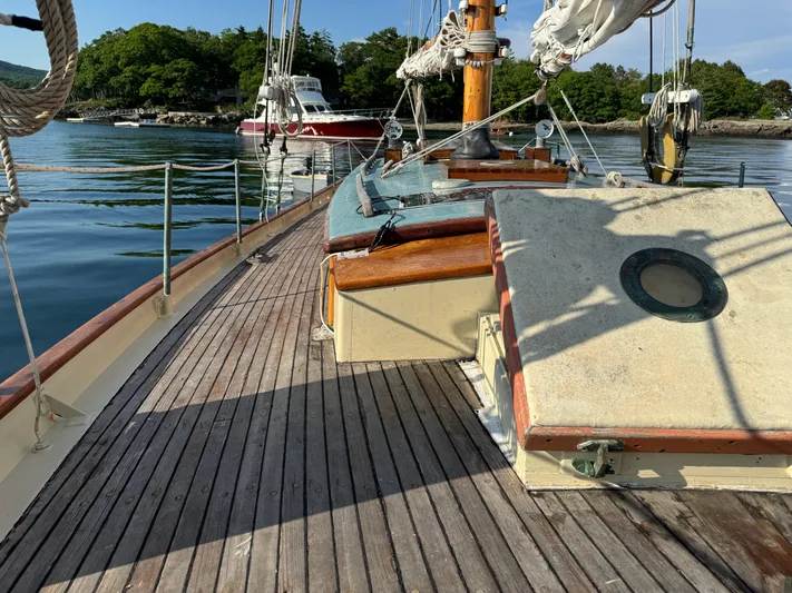 Alyria Yacht Photos Pics Wooden deck of 1996 Custom John Alden Malabar II sailboat, docked in serene waters.