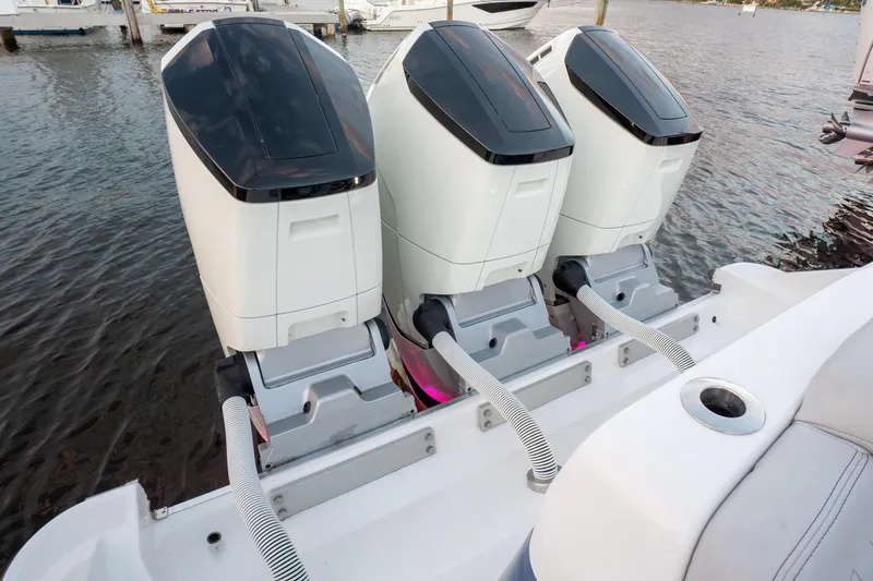  Yacht Photos Pics Triple outboard engines on a 2024 HCB 42 Lujo boat, docked on calm water.