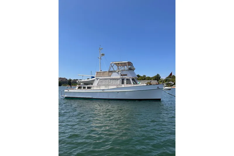 Tiger Moth (reserved) Yacht Photos Pics 1984 Grand Banks 42 Classic yacht on calm water under clear blue sky.