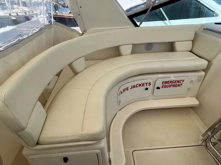 Chaos Yacht Photos Pics 1996 Tiara Yachts 4300 Open interior with curved seating and labeled storage for life jackets and emergency equipment.