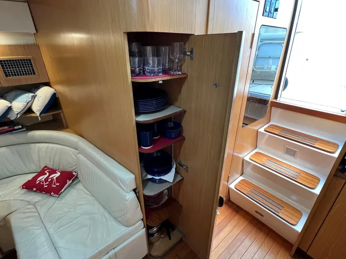 Chaos Yacht Photos Pics 1996 Tiara Yachts 4300 Open interior with wooden cabinetry, white seating, and organized dish storage.