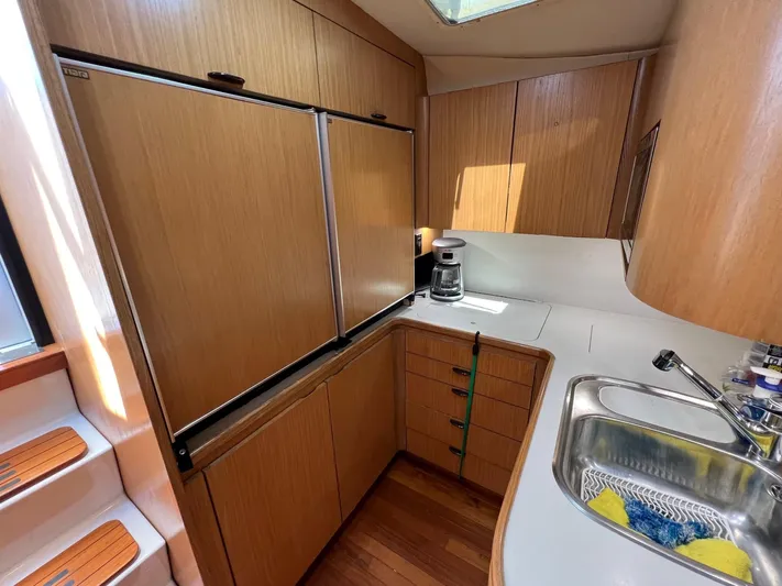 Chaos Yacht Photos Pics 1996 Tiara Yachts 4300 Open galley with wood cabinets, sink, and refrigerator.