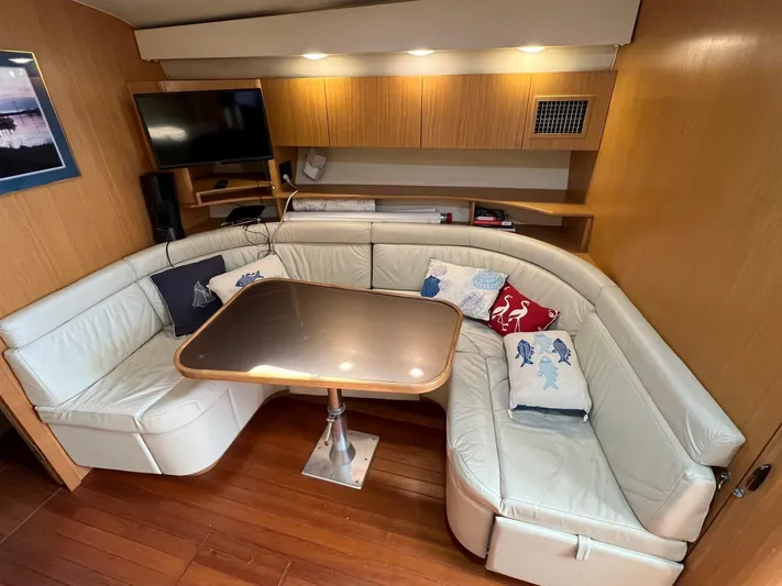 Chaos Yacht Photos Pics 1996 Tiara Yachts 4300 Open interior with leather seating, wooden table, and TV.