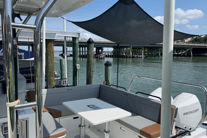  Yacht Photos Pics 2024 Beneteau Flyer 9 SUNdeck boat interior with seating and table, docked by a bridge.
