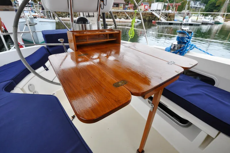 Jezebel Yacht Photos Pics Cockpit of 2004 Sabre 426 sailboat with polished wooden table and blue cushions.