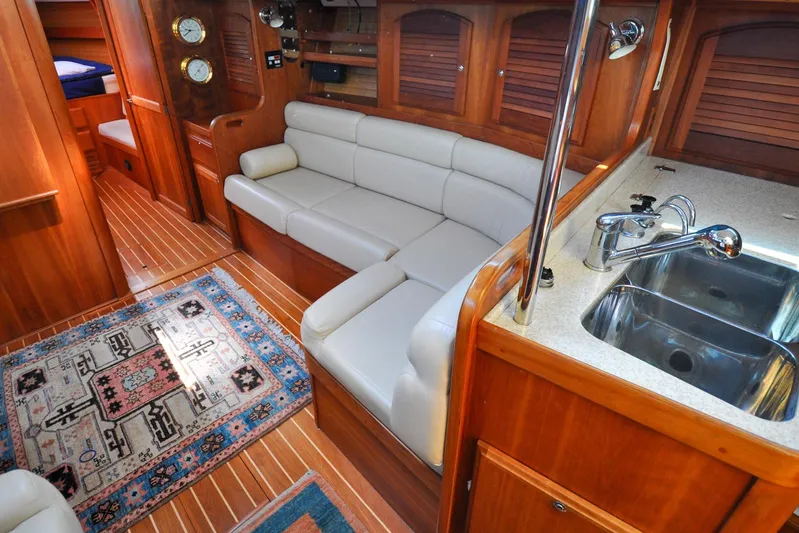 Jezebel Yacht Photos Pics Luxurious 2004 Sabre 426 yacht interior with leather seating, wooden cabinetry, and a compact kitchen area.