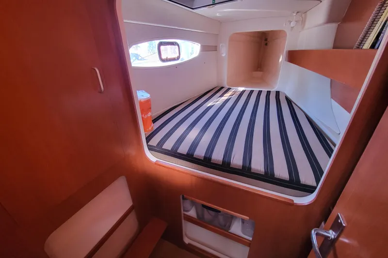 Finding Anemoi Yacht Photos Pics Cabin interior of 2014 Leopard 39 yacht with striped bedding and wooden finish.
