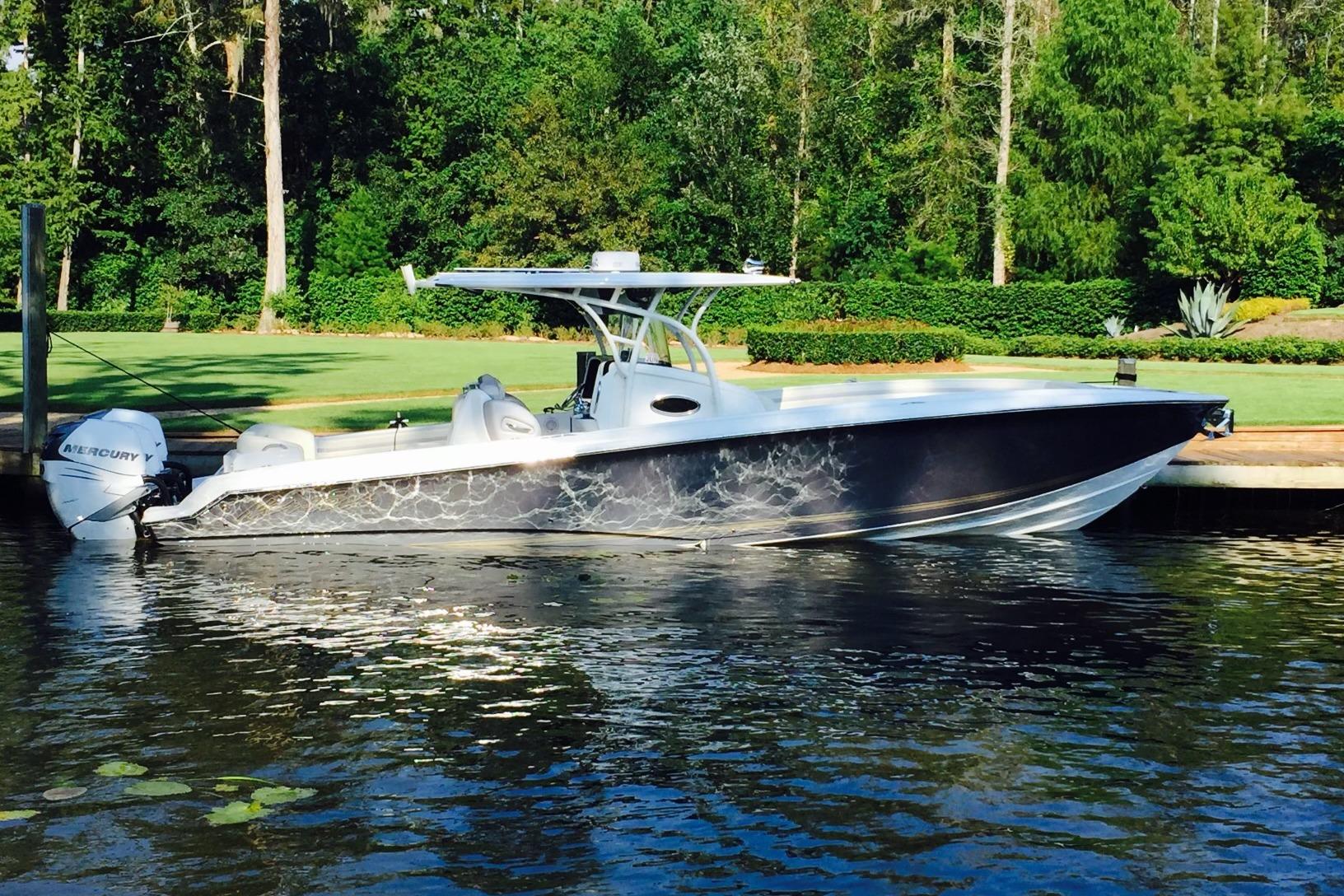 2014 Nor-Tech 340 Sport Center Console boat docked by lush greenery.