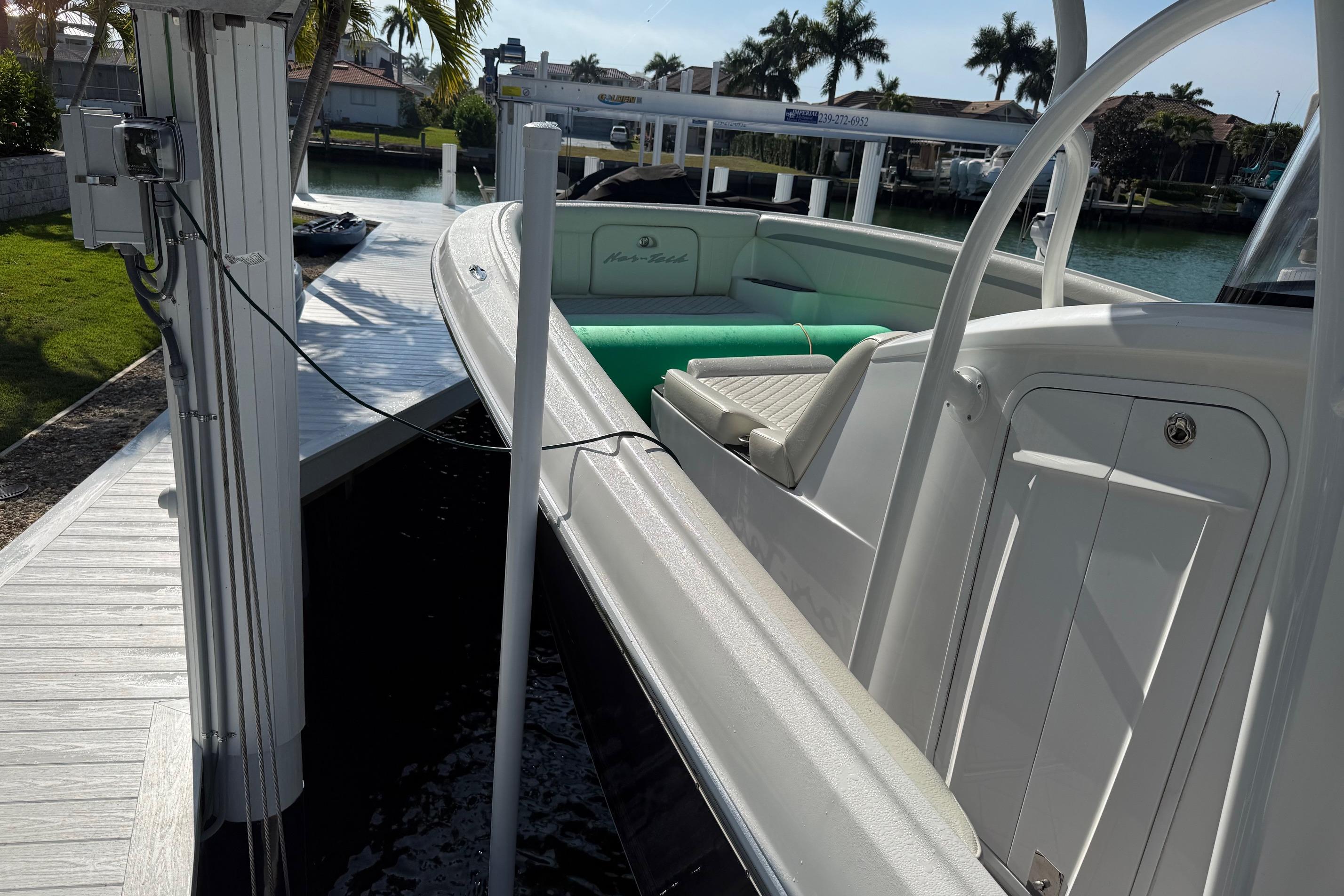 2014 Nor-Tech 340 Sport Center Console docked by a waterfront with palm trees.