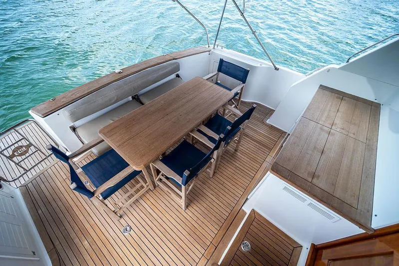 Compass Yacht Photos Pics 2020 Grand Banks 44 Eastbay SX yacht deck with wooden table and chairs, overlooking the water.