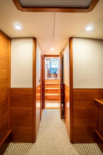 Compass Yacht Photos Pics Interior hallway of 2020 Grand Banks 44 Eastbay SX yacht, featuring wood paneling and carpeted flooring.
