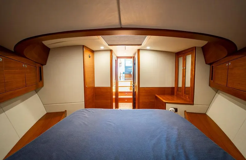 Compass Yacht Photos Pics Luxurious cabin interior of 2020 Grand Banks 44 Eastbay SX yacht, featuring wood finishes and cozy bedding.
