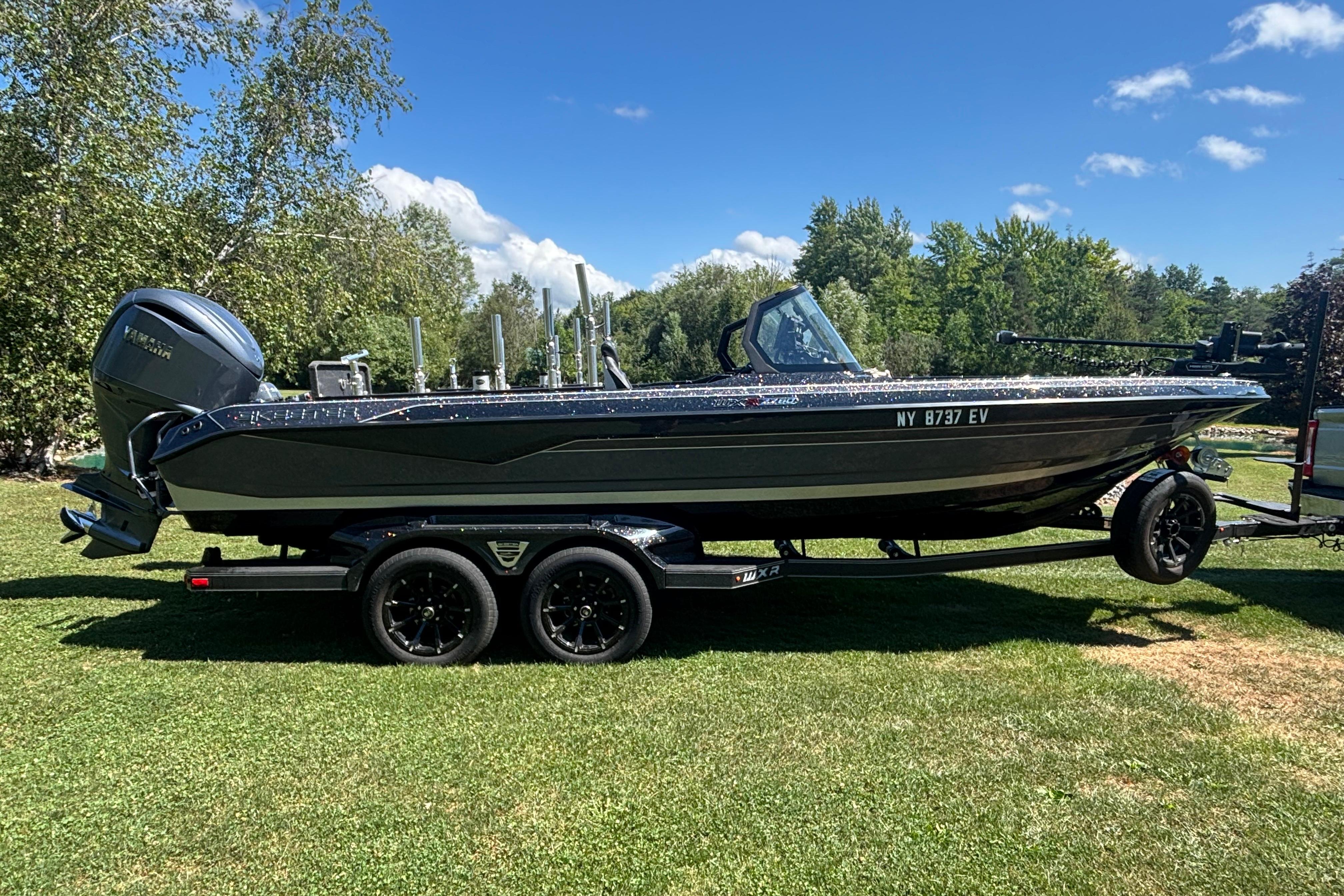 2025 Skeeter WXR2260 boat on trailer, parked on grass under clear blue sky.