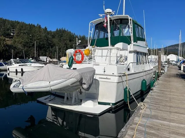  Yacht Photos Pics 2000 Mainship 430 Trawler docked at marina with covered dinghy and scenic background.