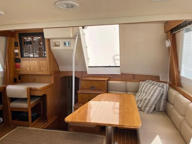  Yacht Photos Pics Interior of 2000 Mainship 430 Trawler with wooden dining area and cushioned seating.