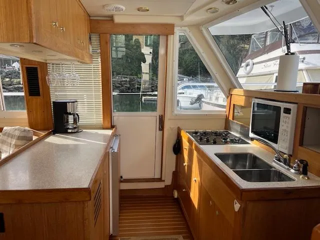  Yacht Photos Pics Interior of 2000 Mainship 430 Trawler kitchen with appliances and wooden cabinetry.