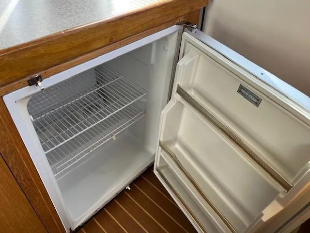  Yacht Photos Pics Open refrigerator inside 2000 Mainship 430 Trawler, featuring wooden cabinetry and wire shelving.