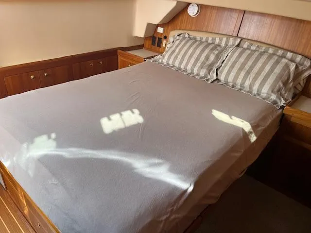  Yacht Photos Pics Cozy bedroom in 2000 Mainship 430 Trawler with wooden cabinetry and striped pillows.