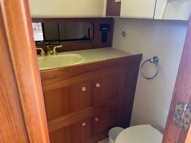  Yacht Photos Pics Bathroom interior of 2000 Mainship 430 Trawler with wooden cabinetry and sink.