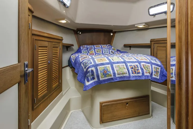 Seeker Yacht Photos Pics 2007 Island Packet SP Cruiser cabin with quilted bed, wooden cabinets, and cozy lighting.
