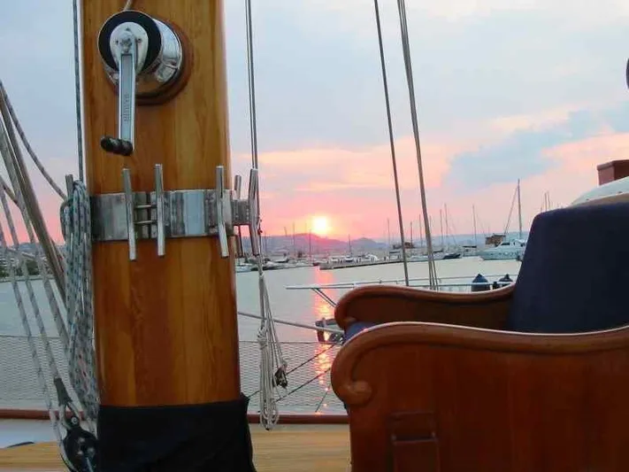 Sea Prince Yacht Photos Pics 1953 Abeking & Rasmussen Motor Sailer at sunset, featuring wooden deck and marina view.