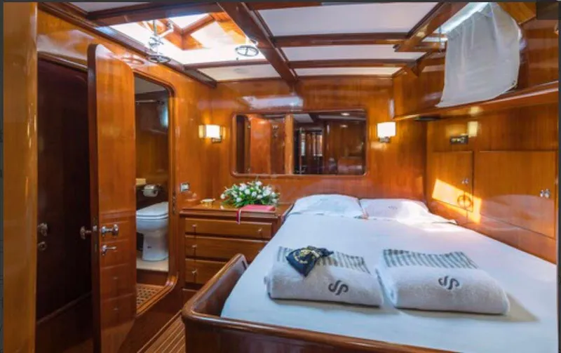 Sea Prince Yacht Photos Pics Luxurious wooden cabin interior of 1953 Abeking & Rasmussen Motor Sailer with bed and bathroom.