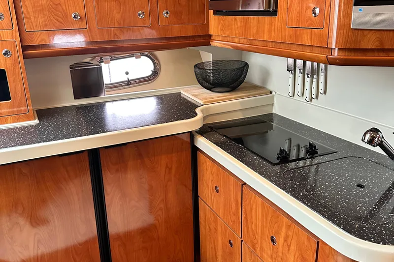  Yacht Photos Pics 2007 Four Winns 378 Vista yacht kitchen with wood cabinets, black countertop, and built-in stove.