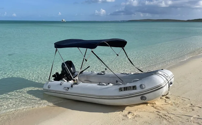 Sea Fever Yacht Photos Pics Inflatable boat with canopy on sandy beach, clear turquoise water in background.