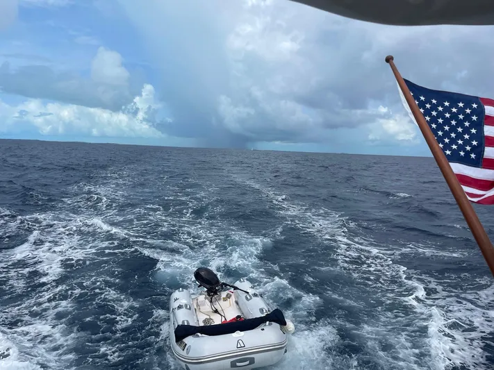 Sea Fever Yacht Photos Pics 1987 Symbol 44 Sun Deck MK II cruising with American flag and dinghy on open sea.