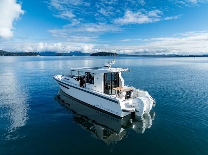 Rylea Rose Yacht Photos Pics Nimbus C11 2021 boat cruising on a calm, scenic lake under a clear blue sky.