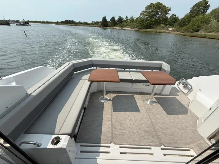 2023 Cruisers 42 Cantius Yacht Photos Pics 2023 Cruisers Yachts 42 Cantius deck with seating and tables, cruising on a scenic waterway.