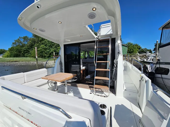  Yacht Photos Pics 2024 Beneteau Antares 12 yacht with spacious deck, seating, and ladder under clear blue sky.