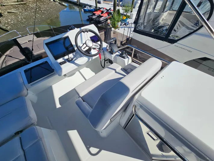  Yacht Photos Pics 2024 Beneteau Antares 12 helm station with modern controls and seating, docked by the water.