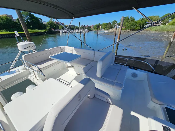  Yacht Photos Pics 2024 Beneteau Antares 12 yacht interior with seating and table, docked by a scenic river.