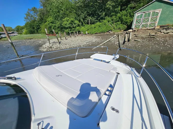  Yacht Photos Pics 2024 Beneteau Antares 12 boat docked near a rustic green boathouse.