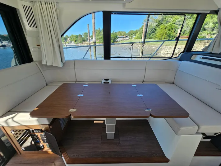  Yacht Photos Pics Interior of 2024 Beneteau Antares 12 yacht with elegant seating and wooden table.