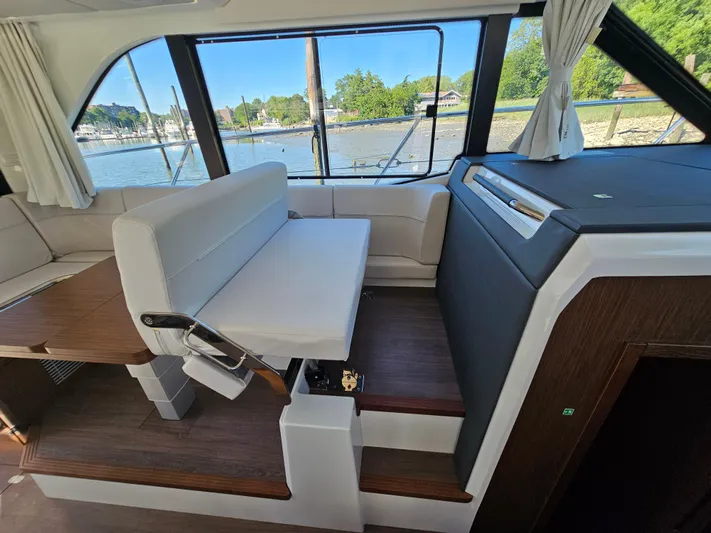  Yacht Photos Pics Interior of 2024 Beneteau Antares 12 yacht with seating and scenic window view.