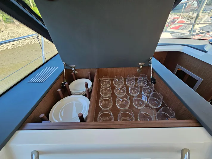  Yacht Photos Pics Storage compartment with glasses and plates on a 2024 Beneteau Antares 12 yacht.