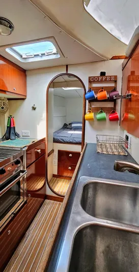 Yacht Photos Pics Interior of 1994 Lagoon 42 yacht with kitchen, colorful mugs, and cozy sleeping area.