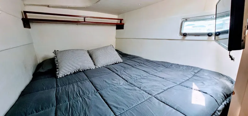  Yacht Photos Pics Cozy cabin interior of a 1994 Lagoon 42 with a comfortable bed and striped pillows.